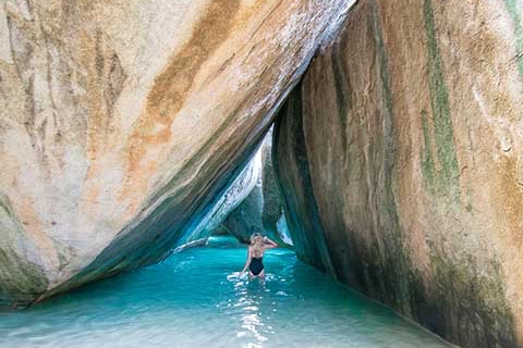 Girl in water between huge boulders